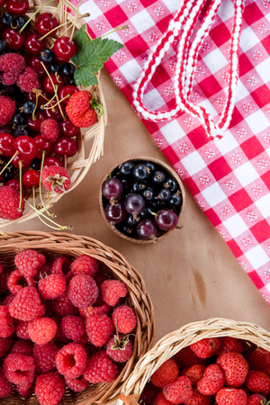 Fresh summer berries in baskets and natural woodの写真素材