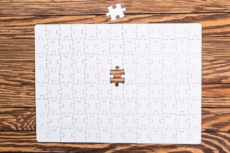 Incomplete white puzzles on the wooden background.の写真素材