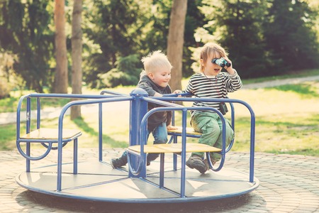 Two happy boys playing on playground in the park. Toned.の写真素材