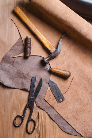Cobbler tools in workshop on a wooden table . Top view.