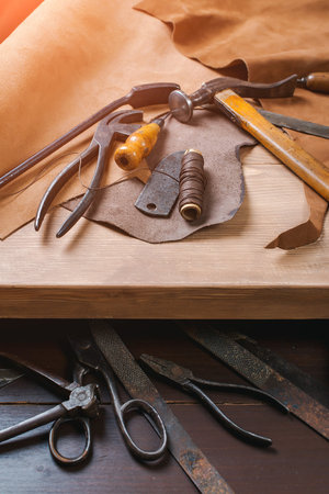 Cobbler tools in workshop on a wooden table . Top view.