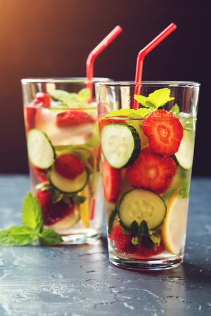 Cold and refreshing infused detox water with strawberry and cucumber in glass on the black background.の写真素材