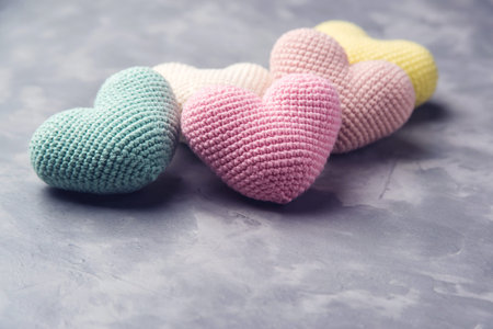 A lot of knitted colorful hearts on the grey textured background. Space for text.
