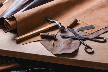 Cobbler tools in workshop on a wooden table . Top view.
