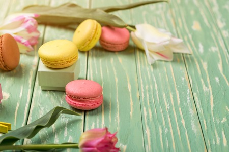 Beautiful tulips with colorful macaroons on the greenery wooden background. Copy space. Selective focus.の写真素材