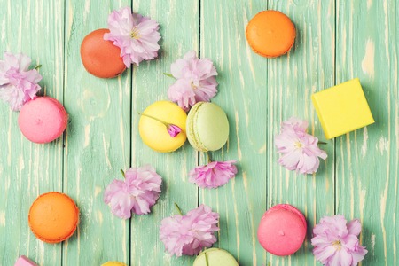 Colorful macaroons with spring sakura flowers on the greenery wooden background. Copy space. Top view.の写真素材