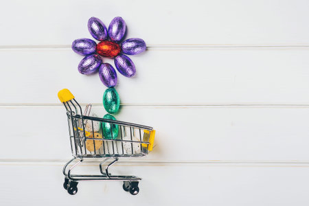 Mini easter eggs wrapped in colored foil forming a flower, in a shopping cart. Spring sale, Easter...