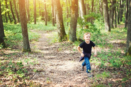 Happy little boy having fun during forest hike on a beautiful summer day.の写真素材