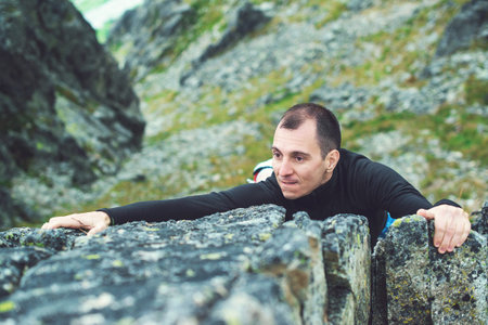 Young man makes hard climbing a steep rock without a rope.の写真素材