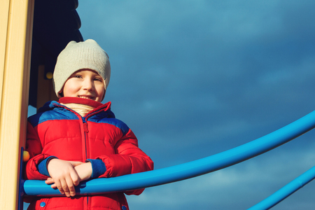 Cute boy having fun on outdoor playground in a cold weather.の写真素材