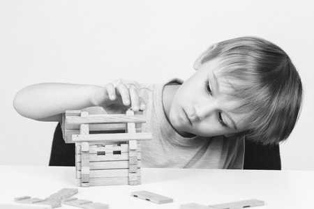 Cute boy building house from wooden blocks. Kid has idea to build house. Happy childhood. Black and white image.の写真素材