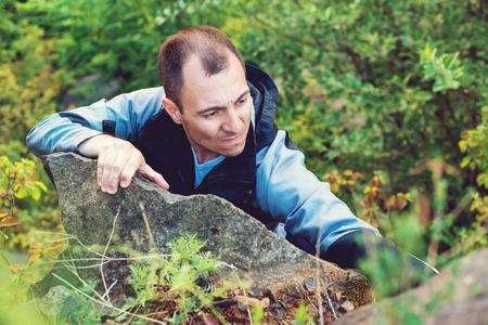 Man climbs on rock. Strong successful male climber. Man climbing the mountain rock. Lifestyle, extreme, success and travel concept. Mountains adventure. Rock climber. Camping, hiking, climbingの写真素材