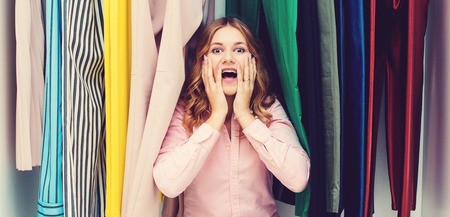 Woman choosing her fashion outfit. Sale, gifts, holidays and people concept. Girl thinking what to wear in front of many choices of clothes in organized wardrobe. Home closet or store clothing rackの写真素材