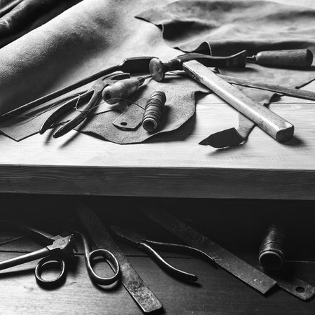 Old tools at table. Pieces of leather at cobbler workplace. Shoemaker's work desk. Leather craft...