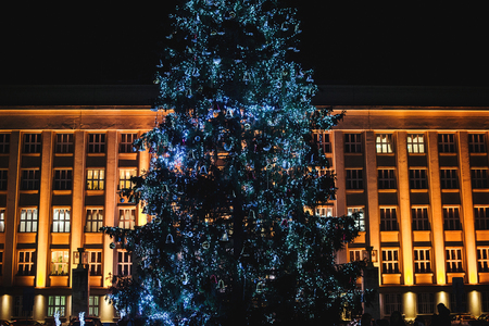 Christmas tree outdoors. Christmas holidays concept. Decorated Christmas tree in front of big buildingの写真素材