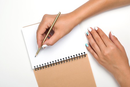 Notebook and pencil in hand. Mock up. Isolated on white background. Woman hands with perfect manicure holding pencil. Woman working. Female workplaceの写真素材