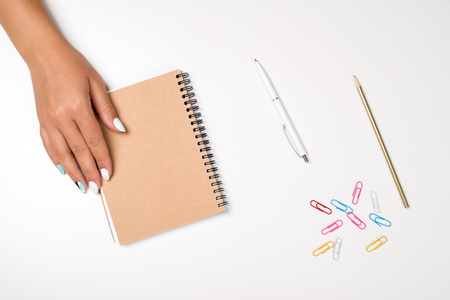 Woman's hands, empty notepad and colorful paper clips on the table. Mockup for your design. Flat lay style. Planning day concept. Working day, creative people, advertising business conceptの写真素材