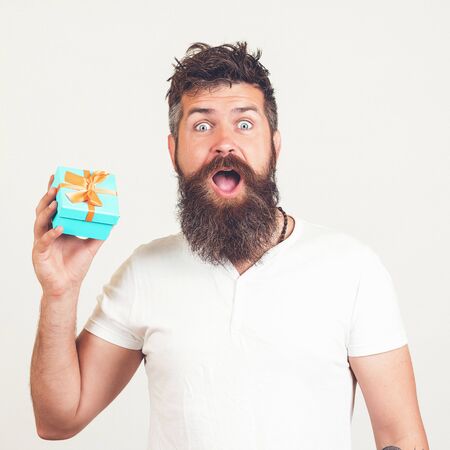 Bearded man with shocked facial expression. Man shows gift box. Hipster surprised by best present ever. Sale concept. Brutal bearded guy with gift box. Holidays, shopping, gifts and seasonal sales.の写真素材