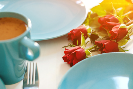 Morning breakfast on kitchen table. Red roses and cup of coffee with milk on table. Romantic breakfast with flowers. Valentine day celebrationの写真素材
