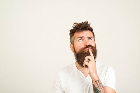 Smart handsome bearded guy having great plan or idea over white background, with copy space. Guy holding his chin and thoughtfully looking aside thinking about his futureの写真素材