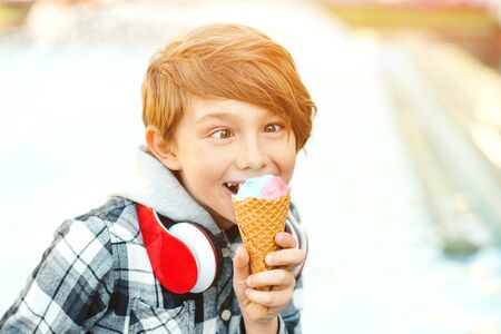 Funny boy eating icecream outdoors. Happy kid having fun. Tasty ice cream. Summer vacation concept. Child holding ice cream in waffles cone. Happy summer holidaysの写真素材