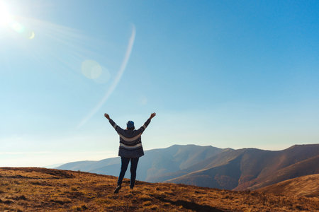 Happy woman rising hands up on top of autumn mountain. Beautiful view on autumn mountains. Travel,...