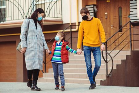 Family going for a walk. Parents and kid wearing a surgical mask. Air pollution concept. Young family wearing protection face mask outdoors. Prevention coronavirus. Coronavirus quarantine.の写真素材