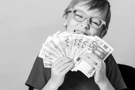Little boy holding fan of money. Money for future education. Cute boy acount his money. Financial literacy of children. Excited child showing big money. Winner, lottery and millionaire.の写真素材