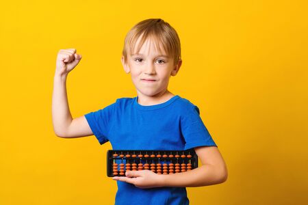 Schoolboy with abacus over yellow background. Kid study at mental arithmetic school. Education and development concept. Mental arithmetic lessons. Back to school. Smart kid, iq.の写真素材