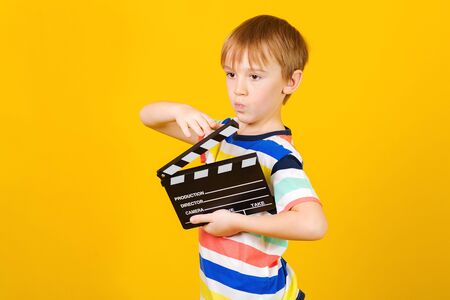 Happy child with clapper board for making video cinema in studio. Movie production clapper board or slate film concept. Kids hobbies and leisure. Little producer making film.の写真素材