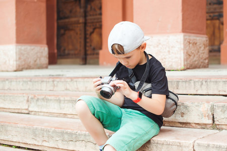 Cute boy wants to be a photographer. Little boy photographing city in summer day. School project for...