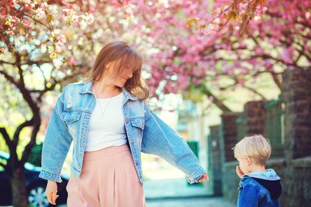 Happy mother and son walking along the spring street. Cute boy and mom having fun together outdoors. Happy mother's day. Family, fashion and vacations. Playful child and young mother enjoy springtime.の写真素材