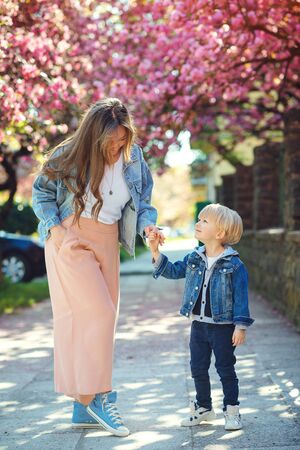 Happy mother and son walking along the spring street. Happy family. Fashion, family and holidays. Family on a walk in city. Happy mother's day. Cute stylish child and mom outdoors. People, lifestyleの写真素材