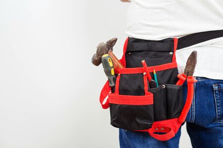 Worker belt with construction tools, closeup. Builder wearing belt with instruments for housework. Isolated on white, copy space. Construction worker with tool belt. House renovation concept.の写真素材