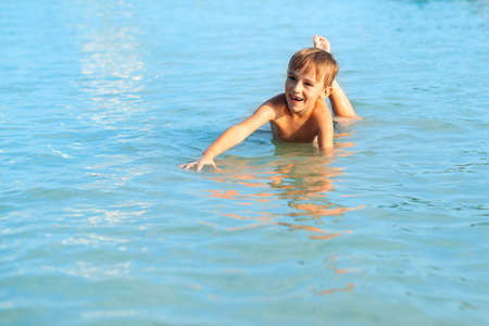 Happy child playing in the sea. Cute boy swimming in water. Kid having fun at the beach. Summer vacation. Active lifestyle concept. Happy kid on summer vacations.の写真素材