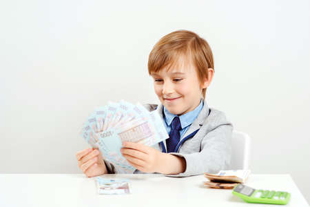 Little businessman holding money banknotes. Winner, lottery and millionaire. Financial literacy of children. Saving money for future education. Money and savings concept.の写真素材