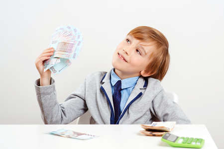 Little businessman holding money banknotes. Winner, lottery and millionaire. Financial literacy of children. Saving money for future education. Money and savings concept.の写真素材