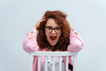Young beautiful girl shouting and looking at camera. Hipster girl in eyewear sitting at chair....