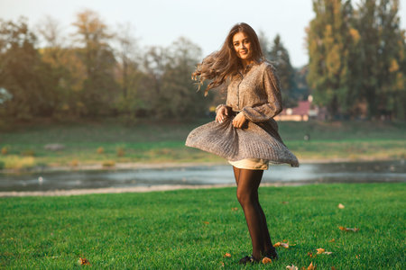 Fashionable model girl dancing on a walk at nature. Fashion and beauty. Luxury woman in trendy dress at sunset. Dream, carefree, freedom and happiness concept. Happy girl enjoying autumn.の写真素材