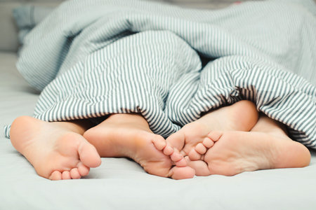 Feet of a young couple lying on the bed at honeymoon. Passionate love. Love lying in bed in hotel....