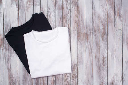 Mockup with two blank t-shirt. Black and white color t-shirts on wooden background for presentation. Copy space for your design.の写真素材