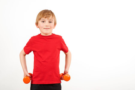 Cute boy with dumbbells. Schoolboy training with dumbbells, isolated on white. Physical training for...