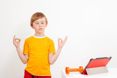 Remote workout. Boy doing yoga exercise at home. Children sports during quarantine. Online workout....