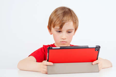 Smart boy using gadget during online lesson. Online education during quarantine. Homeschooling concept. Remote learning and schooling. Coronavirus pandemic. Child studying from home. Remote education.の写真素材
