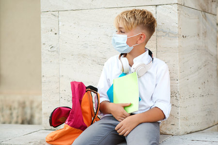Tired boy in safety mask after lessons. Education during pandemic. School boy wearing face mask for...