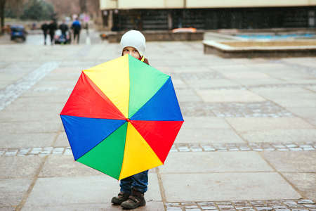 Child with umbrella outdoors. Kid having fun under umbrella. Rainy weather. Happy childhood. Cute little boy walking the street on rainy day.の写真素材
