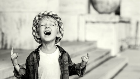 Cute child showing horns up gesture. Excited little boy screaming and doing heavy metal rock sign....