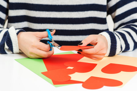 Girl makes greeting heart for Valentine's Day, close up. DIY greeting card. Love, romantic, letters....