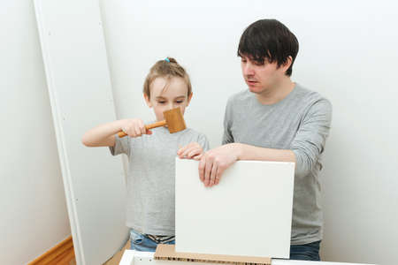 Dad and little son assembling furniture at home. Furniture assembly yourself. Father helps his son to assemble a bookshelf. Fatherhood, relationship and family concept.の写真素材
