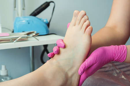 Feet treatment. Beauty treatment for legs. Pedicure master massaging feet with scrub. Professional pedicure in the beauty salon. Woman relaxing at salon, caring about nails.の写真素材